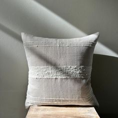 a white pillow sitting on top of a wooden table next to a gray and white wall