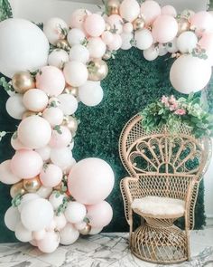 a chair sitting in front of a green wall with balloons hanging from it's sides