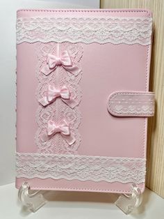 a pink card with white lace and bows on the front is sitting on a stand