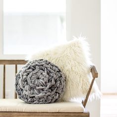 a white and gray pillow sitting on top of a wooden chair