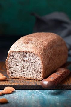 a loaf of bread sitting on top of a wooden cutting board next to two almonds