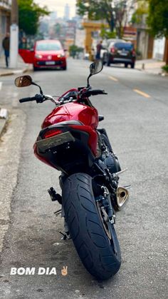 a red motorcycle is parked on the side of the road in front of some cars