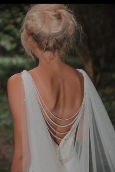 the back of a woman's wedding dress with pearls on her neck and shoulders