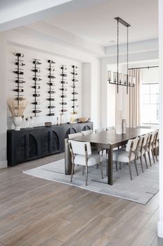 a dining room table with white chairs and shelves on the wall behind it in front of a fireplace