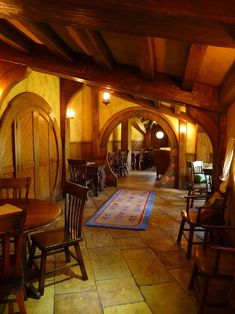 a room with chairs, tables and rugs on the floor in front of an archway