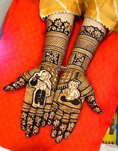 two hands with henna designs on them sitting on top of a red cloth covered chair