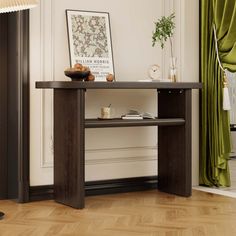 a wooden table sitting on top of a hard wood floor next to a green curtain