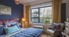 a bed room with a neatly made bed next to a large window and a chair