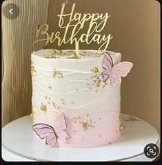 a pink and white cake with gold butterflies on it's top that says happy birthday