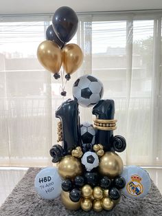 an arrangement of balloons, soccer balls and other items are on display in front of a window