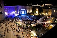 an aerial view of a concert venue at night with people standing in the foreground