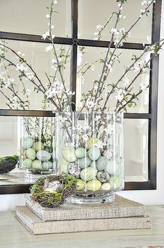 two vases filled with flowers and eggs sitting on top of a table next to a mirror