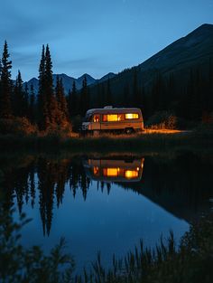 a camper van is parked in front of a lake at night