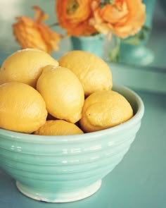 a blue bowl filled with lemons on top of a table