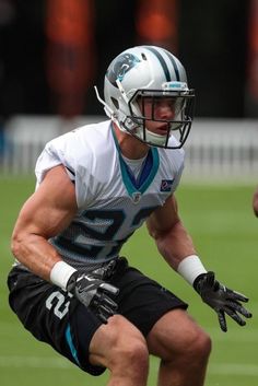 a football player is running with the ball in his hand while wearing black shorts and a white helmet