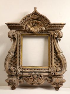 an old wooden frame with carvings on the sides and a white wall in the background