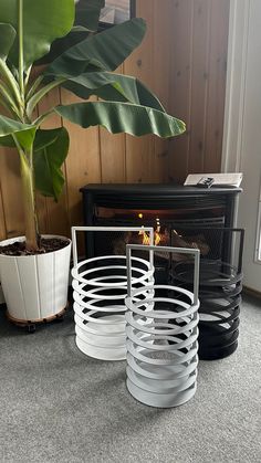 three white circular plant stands in front of a fireplace with a potted plant next to it