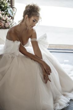 a woman in a wedding dress sitting on the floor