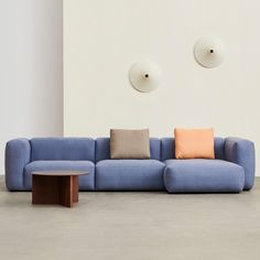 a blue couch sitting next to a wooden table in a room with two circular lights on the wall