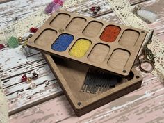 two wooden trays with different colored beads in them on top of a table next to scissors