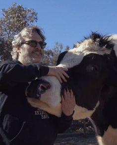 a man is petting a black and white cow