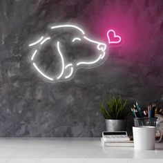 a neon pig head with a heart on it's nose next to a desk