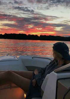 a woman sitting on the back of a boat at sunset