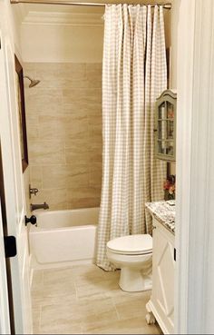 a white toilet sitting in a bathroom next to a bath tub under a shower curtain