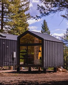 a small cabin in the middle of a forest with its door open and windows opened