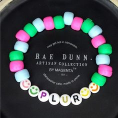 a black plate topped with lots of colorful beads and plastic name charms on it's side