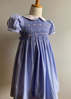 "Here is a sweet, sweet classic from the 80's. It carries the label, \"Angel Fish\" and it is hand smocked and embroidered. 100% cotton, it is made from a small, woven, blue and white gingham. Both front and back bodices are lined in gingham, while an all cotton white petticoat is attached to waist, providing fullness.  The dress was made in the Phillipines, a center for beautiful handwork.                                                      The front bodice is entirely shirred, then smocked in Cotton Smocked Lined Dress For Daywear, Cotton Smocked Dress Lined For Daywear, Cotton Fitted Smocked Dress, Fitted Vintage Smocked Dress For Summer, Vintage Smocked Summer Dress, Vintage Smocked Bodice Summer Dress, Cotton Gingham Smocked Dress With Ruffles, Cotton Smocked Dress With Ruffles In Gingham, Gingham Cotton Smocked Dress With Short Sleeves