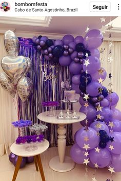 purple and silver balloons are hanging from the ceiling next to a table with cake on it