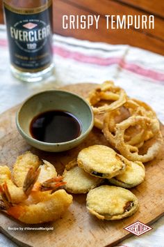 crispy tempura on a wooden plate with dipping sauce and onion rings in the foreground