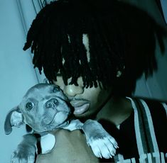 a woman holding a dog in her arms with dreadlocks on it's head