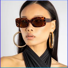 a woman wearing large hoop earrings and tortoise shell sunglasses