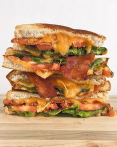 a stack of bacon, lettuce and cheese sandwiches on toasted bread with melted cheese