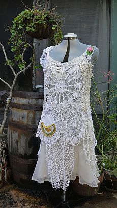 a white crochet top on a mannequin next to a potted plant