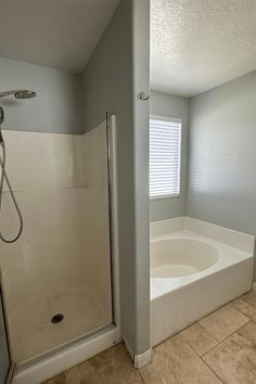 a bathtub and shower in a bathroom with tile flooring, white walls and ceiling