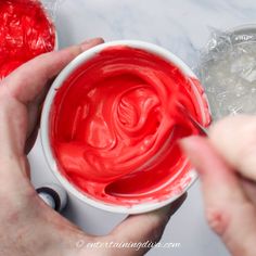 someone is painting the inside of a cup with red paint