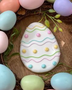 a decorated easter egg sitting on top of a wooden table next to eggs and greenery