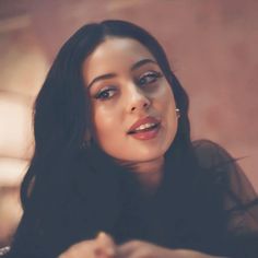 a close up of a woman with long hair and wearing a black shirt looking off to the side