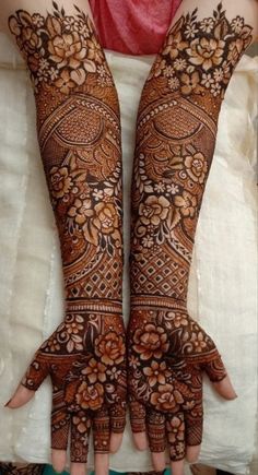 two hands with henna designs on them, one is showing the intricate design and the other has flowers