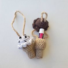 two crocheted items are sitting on a white surface and one has a pen in it