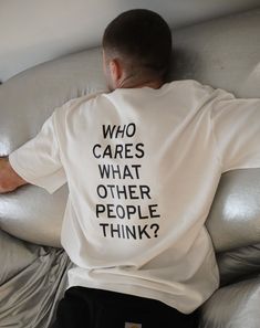 a man sitting on top of a couch wearing a white shirt that says who cares what other people think?