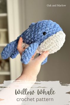 a hand holding a crocheted blue and white stuffed animal with the words willow whale on it