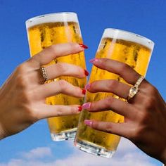 two women toasting with beer glasses in front of blue sky and white fluffy clouds