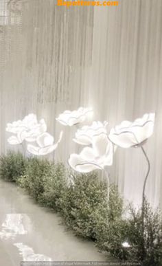 an artistic display with white flowers and greenery in front of a curtained wall