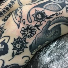 a close up of a person's leg with tattoos on it and flowers in the background