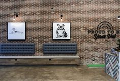 an office with brick walls and benches in front of the wall is decorated with art