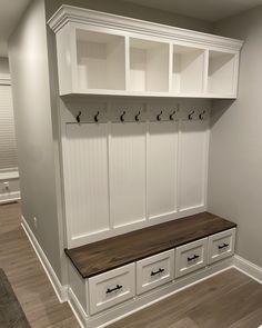 an empty room with some white cabinets and drawers on the wall next to a wooden bench